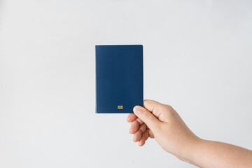 Hand holding a blue passport with a blank cover and the biometric symbol on a white background