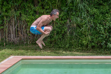 Middle-aged man cannonball dives into swimming pool shouting