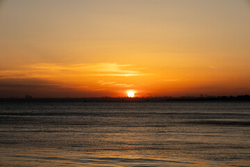 Stunning Sunset Over the Calm Waters with a City Skyline in the Distance