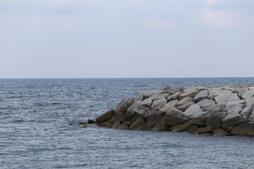 A seaside with a rocky reef extending into the sea .