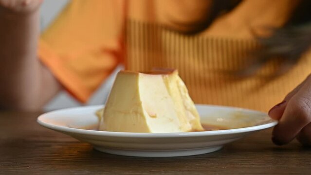 Woman cutting a pudding for eat by spoon. Pudding is a popular dessert and snack. It tastes sweet, and comes in many flavors.