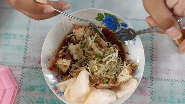 Indonesian food called "Tahu Guling". Contains sliced cabbage, slices of "bacem" tofu and tempeh, bean sprouts, ketupat, celery and fried onions as toppings. 