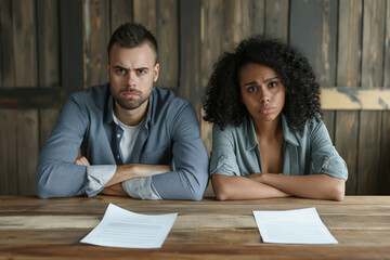 Obraz premium Upset couple at table with divorce papers. A poignant depiction of a couple facing a divorce. Perfect for illustrations related to legal services, relationship issues, and divorce lawyer consultation.