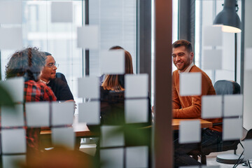 In a sleek glass office space, a team of business professionals engage in lively discussions and exchange strategic ideas, showcasing collaboration and innovation at the heart of modern corporate