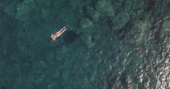 Aerial view of woman swimming in clear blue water, Salina Island, Italy.