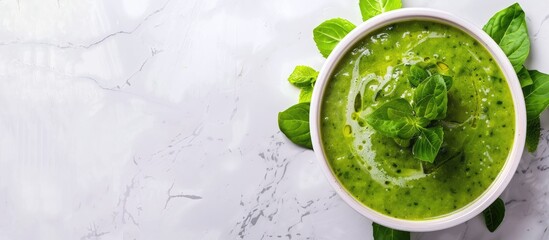 Obraz premium A vibrant spring vegetable soup displayed on white marble with copy space, seen from above.
