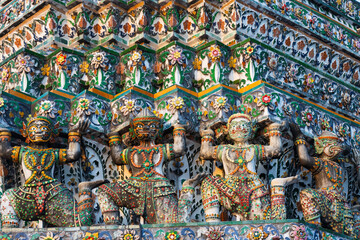 Colorful Mythological Monkey or Yaksha supporting figures decorating the prang of Wat Arun, Bangkok, Thailand. Prang and statues decorated with elaborate porcelain patterns. Wat Arun or Temple of Dawn