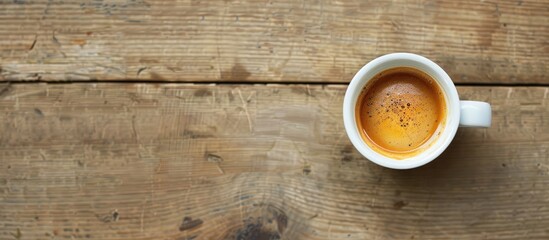 Obraz premium A top-down view of a white espresso cup on a wooden surface, offering a clear area for additional imagery.