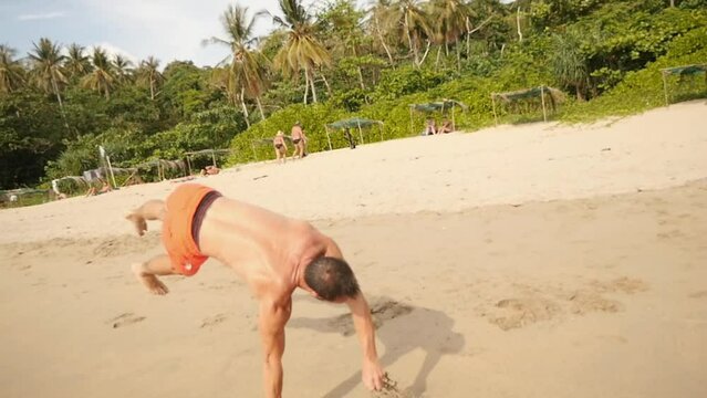 A man does a backlip in slow motion on a heavenly beach in Koh Lanta, Thailand
