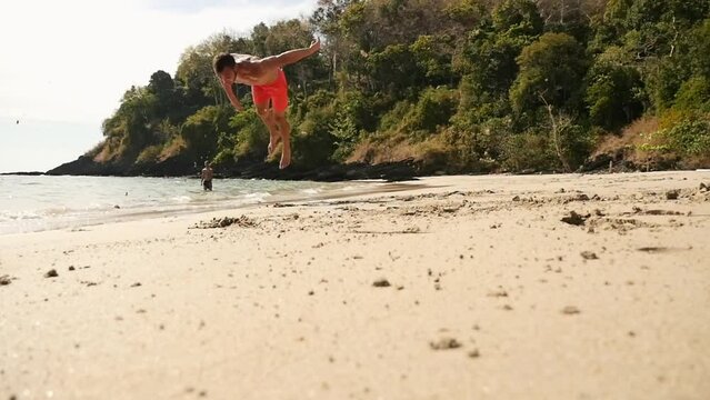 A man does a backlip in slow motion on a heavenly beach in Koh Lanta, Thailand