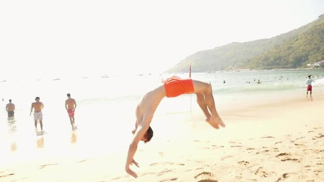 A man does a backlip in slow motion on a heavenly beach in Koh Lanta, Thailand
