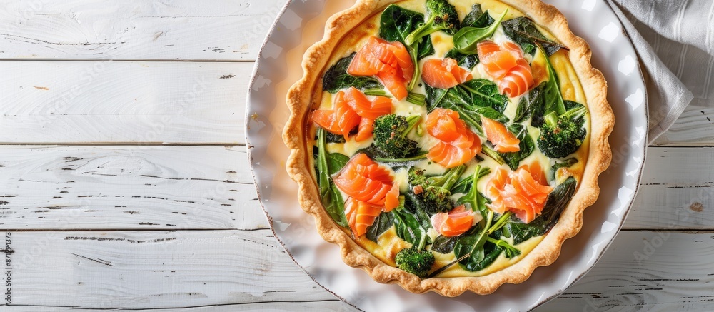 Aufkleber top-down view of a quiche tart containing smoked salmon, broccoli, and spinach on a white wooden bac
