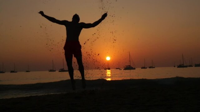 A man does a backlip in slow motion at sunset in Koh Lanta, Thailand
