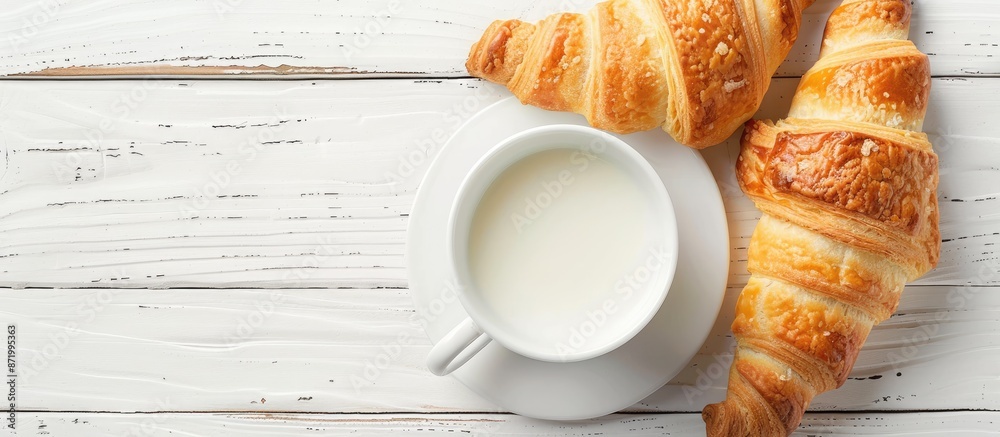 Poster a cup of milk and crescent rolls displayed on a white wooden table, with a clear view from above, id