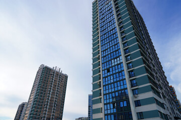 Fototapeta premium Facade building on blue sky background. Modern building, houses. Colorful buildings with glass windows, balconies. Buildings architecture. Skyline Skyscrapers. Urban Residential building exterior.