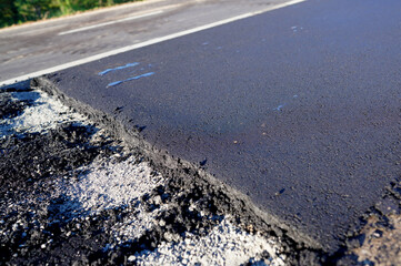 Asphalt road after laying asphalt. New asphalt road renovation. Road construction. Paved sidewalk. Black tarmac pedestrian road, repair. Black tarmac rebuilding. Street Asphalting.