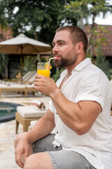 man drinking juice by the pool