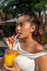 asian woman drinking juice by the pool