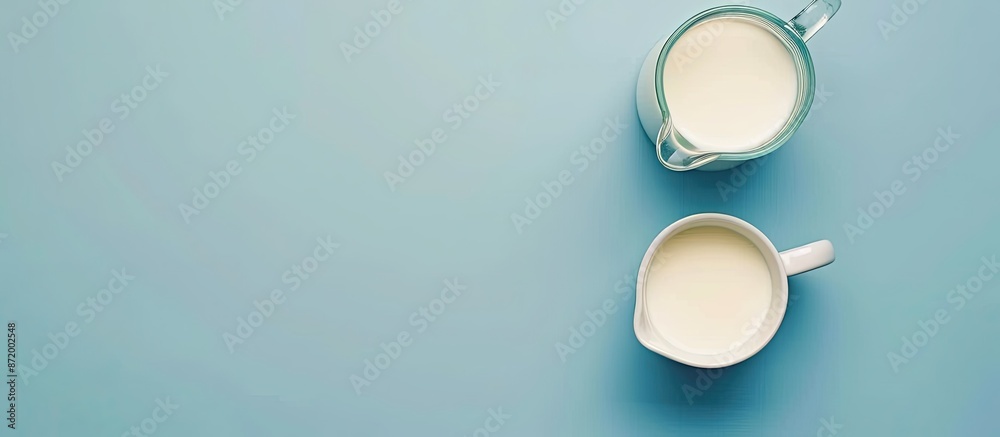 Poster top view of a jug and glass of milk on a blue backdrop with copy space image.
