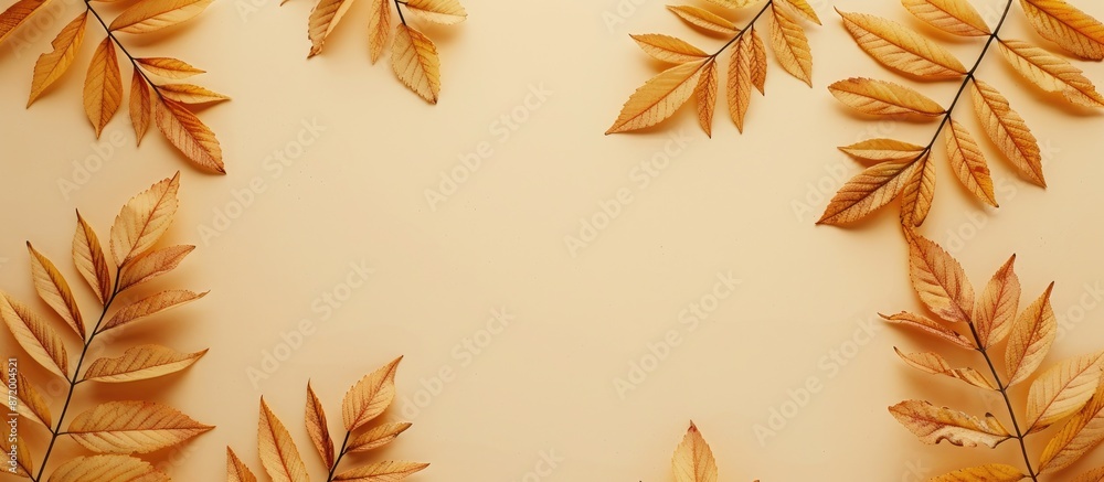 Poster A flat lay view of autumn rowan leaves in golden hues displayed on a beige backdrop with ample copy space, symbolizing the essence of the fall season.