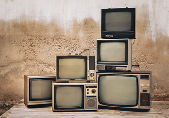 Retro old televisions pile on floor in front of old brick wall. Antique and vintage style photo, retro TVs blank screen display