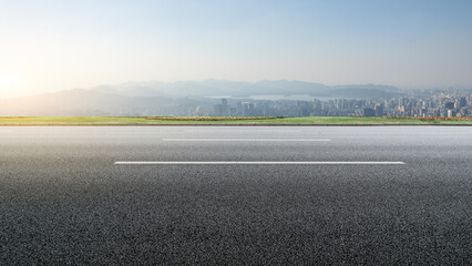Fototapeta premium Open Road Leading to Urban Skyline at Sunrise