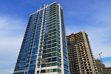 Obraz premium Facade building on blue sky background. Modern buildings exterior with glass windows, balconies. Buildings architecture. Skyline Skyscrapers. Tower crane on Construction of the Residential building.