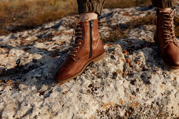 Brown boots standing on top of a rock in the middle of a field in the wilderness
