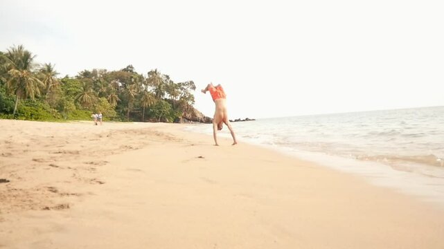 A man does a backlip in slow motion on a heavenly beach in Koh Lanta, Thailand