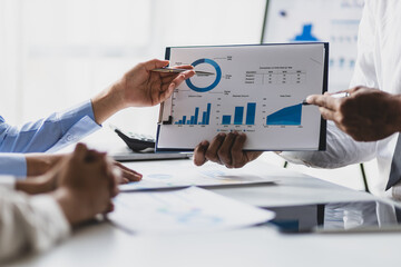 Business consulting meeting is discussing business plan analysis with financial data and business growth charts to plan strategies for generating company profits.