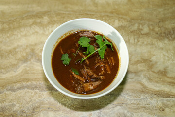 Top view of a bowl with Mexican homemade beef birria in consommé.