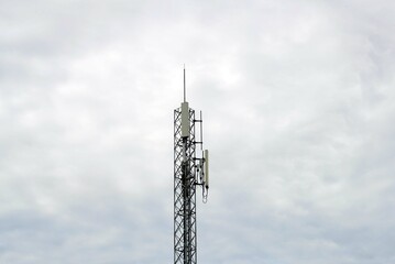 A telecommunication tower against the blue sky with white clouds.
