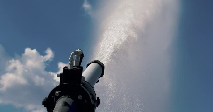 Super slow motion close up of automatic industrial agricultural irrigation system is spraying water with splashing crystal clear pure water drops for watering crops and plants on field at 1000 fps.