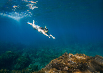 Fototapeta premium Woman snorkeling under water in a turquoise sea