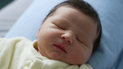 Newborn baby sleeping with a peaceful expression, resting on a blue pillow. delicate features and serene atmosphere, innocence and tranquility of newborn life