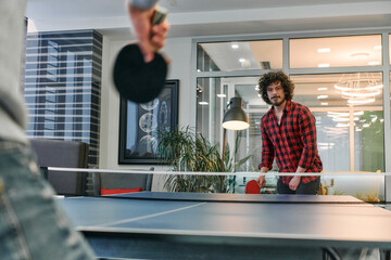 Obraz premium Business colleagues take a break from work to enjoy a game of table tennis, fostering teamwork and camaraderie in the workplace