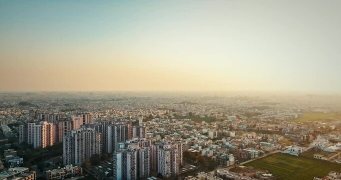 Aerial panoramic view of Mohali City in Punjab, India, bathed in golden sunset hues. The drone moves right to left, revealing the tranquil beauty of the urban skyline.