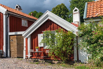 Kalmar a beautiful town in the south of Sweden. Travel touristic Landmark. Traditional little red wooden houses. Beautiful small house with clay tile roof. Cozy table and chairs outside for rest.  © GenоМ.