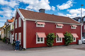 Kalmar a beautiful town in the south of Sweden. Travel touristic Landmark. Bright colorful old wooden houses. The girl is standing next to the bike. Amazing view of traditional wooden swedish houses. © GenоМ.