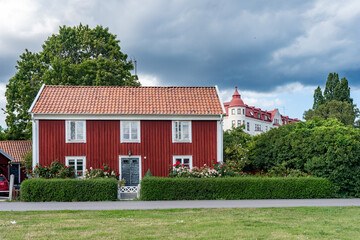 Kalmar a beautiful town in the south of Sweden. Travel touristic Landmark. Traditional little red wooden houses. Beautiful small cozy house with clay tile roof. Plants and roses decorates home entre.  © GenоМ.