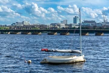 Small sailboat anchored on the Charles River with Boston Skyline in the Background, Massachusetts, USA