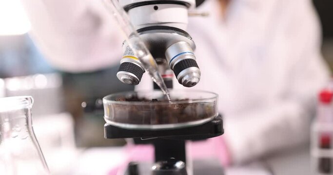 Scientist adds liquid to glass flask with earth in laboratory. Effect of toxic and poisonous liquids in soil concept