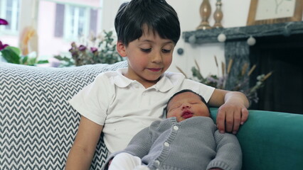 Young boy gently cradling his newborn sibling on a couch, surrounded by cozy home decor, showcasing a quiet and affectionate moment of sibling bonding. Highlights themes of family love and connection