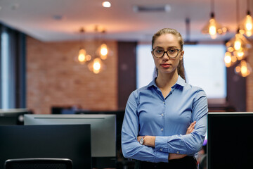 Obraz premium Confident Businesswoman: Blonde Executive Demonstrating Leadership with Crossed Arms.
