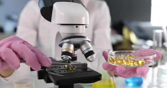 Scientist examines properties and benefits of omega-3 fatty acids using microscope. Medical laboratory and benefit of vitamin and amino acids concept