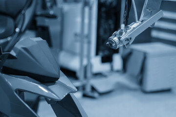 Close up scene the automatic painting robot working with motorcycle parts in the light blue scene.