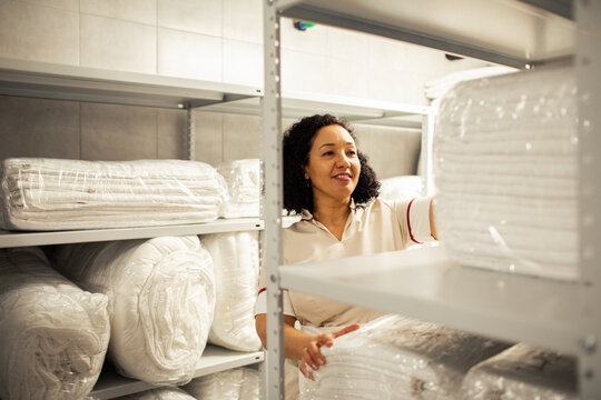 Woman maid organizing linens in a hotel storage room