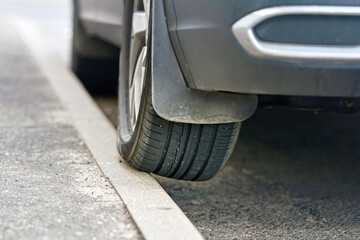 Wheel on curb, traffic violation. Car parked on curb, tire and wheel closeup. Parked car with one...