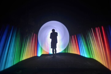 One person standing alone against a Colourful circle light painting as the backdrop	