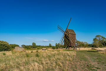 Naklejka premium Beautiful windmill. Countryside landscape with old traditional wooden windmill in rural area of southern Sweden.